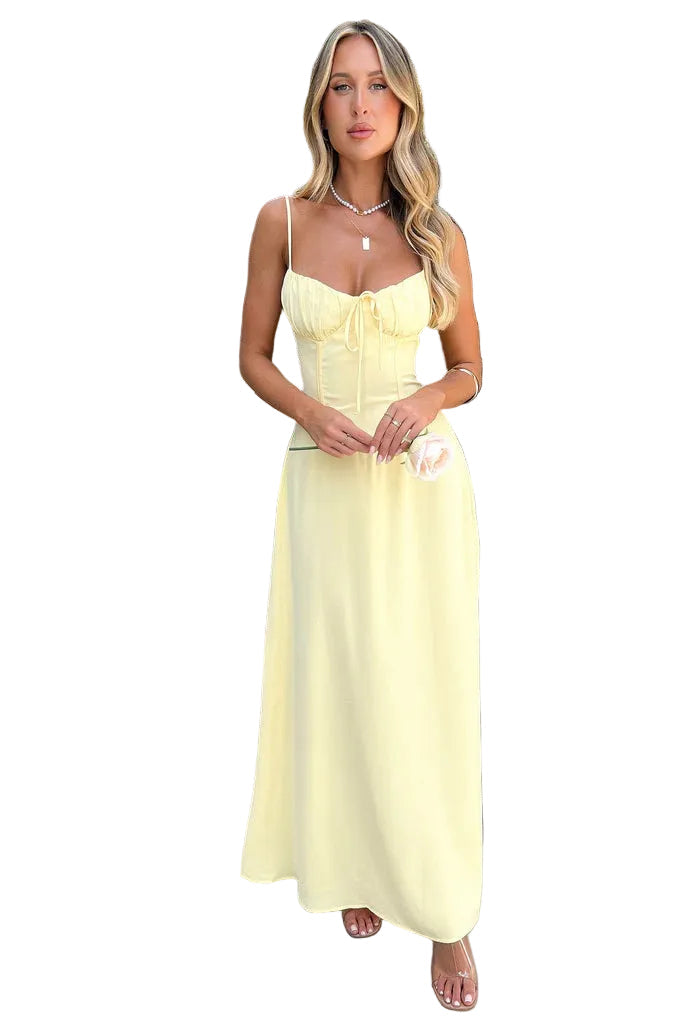 Front view of a woman in a pale yellow summer maxi dress, featuring a ruched bust and elegant A-line skirt, holding a single rose.