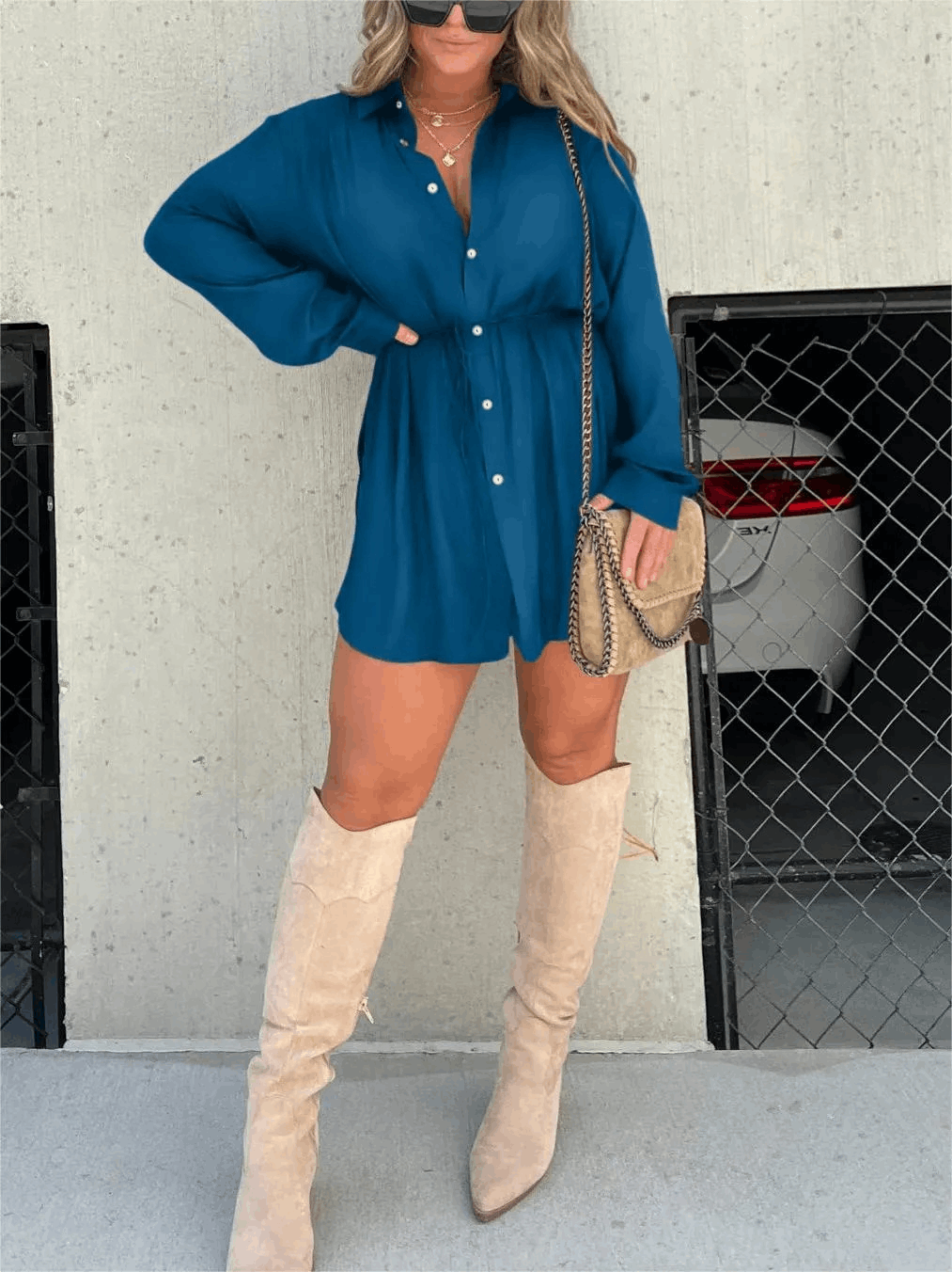 Teal long sleeve button front mini romper with a relaxed fit, cinched waist, and white buttons, styled with light boots.