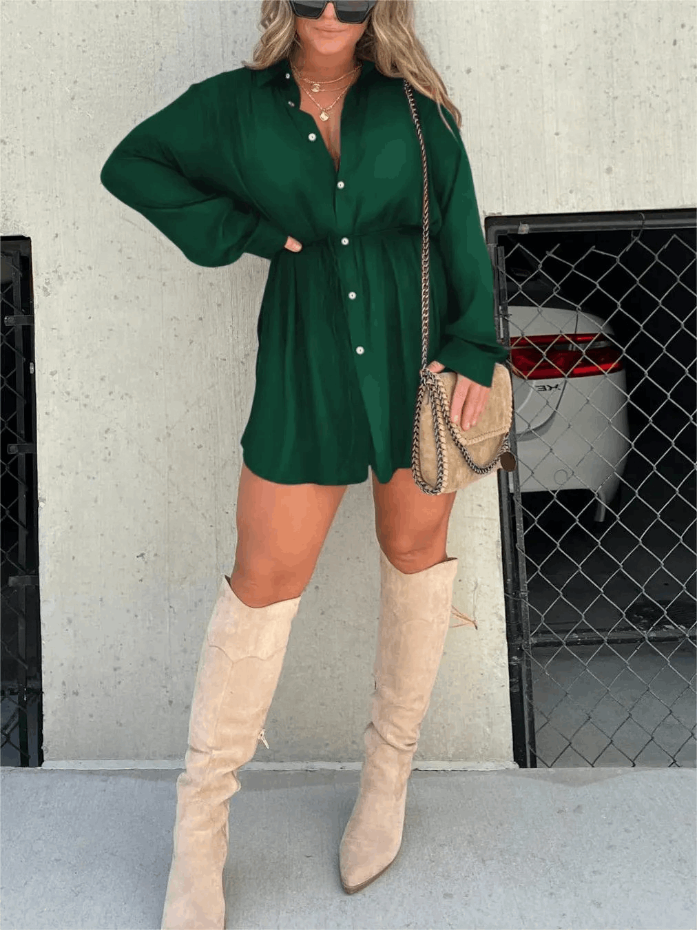 Emerald green long sleeve button front mini romper with cinched waist, styled with tall beige boots and a crossbody bag.