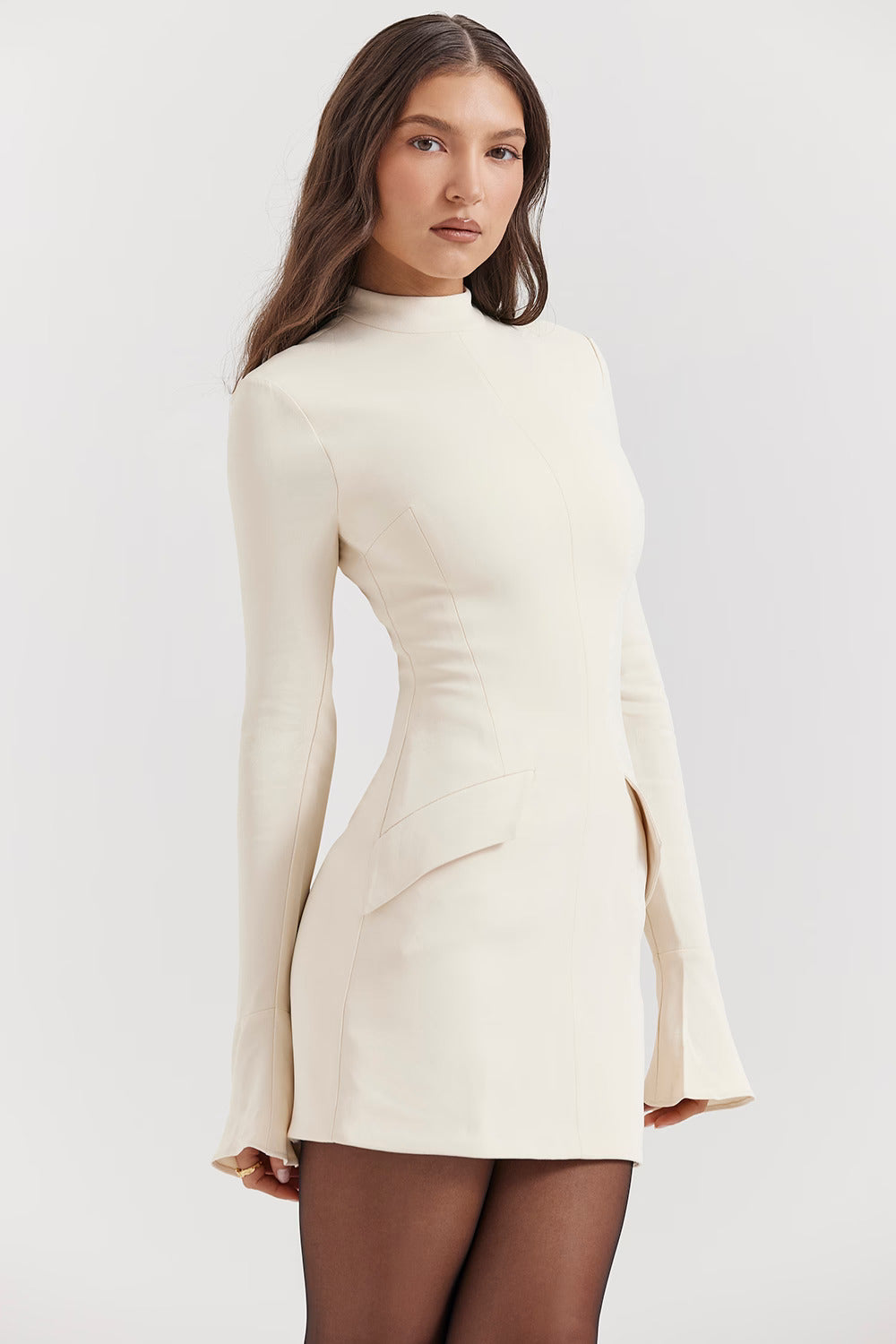 Close-up of the cream long sleeve high neck mini dress, highlighting the structured bodice and subtle pocket detail.