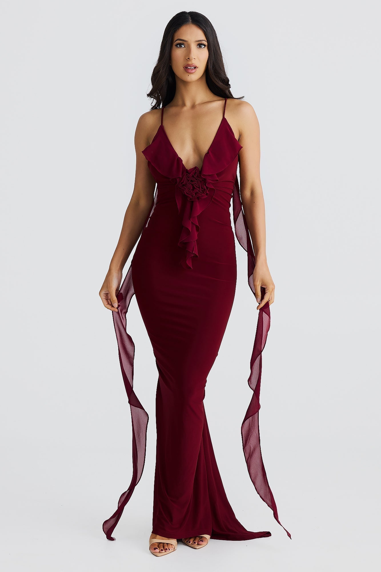 Front view of burgundy low back maxi dress with plunging neckline and rose feature, womens wedding guest dresses