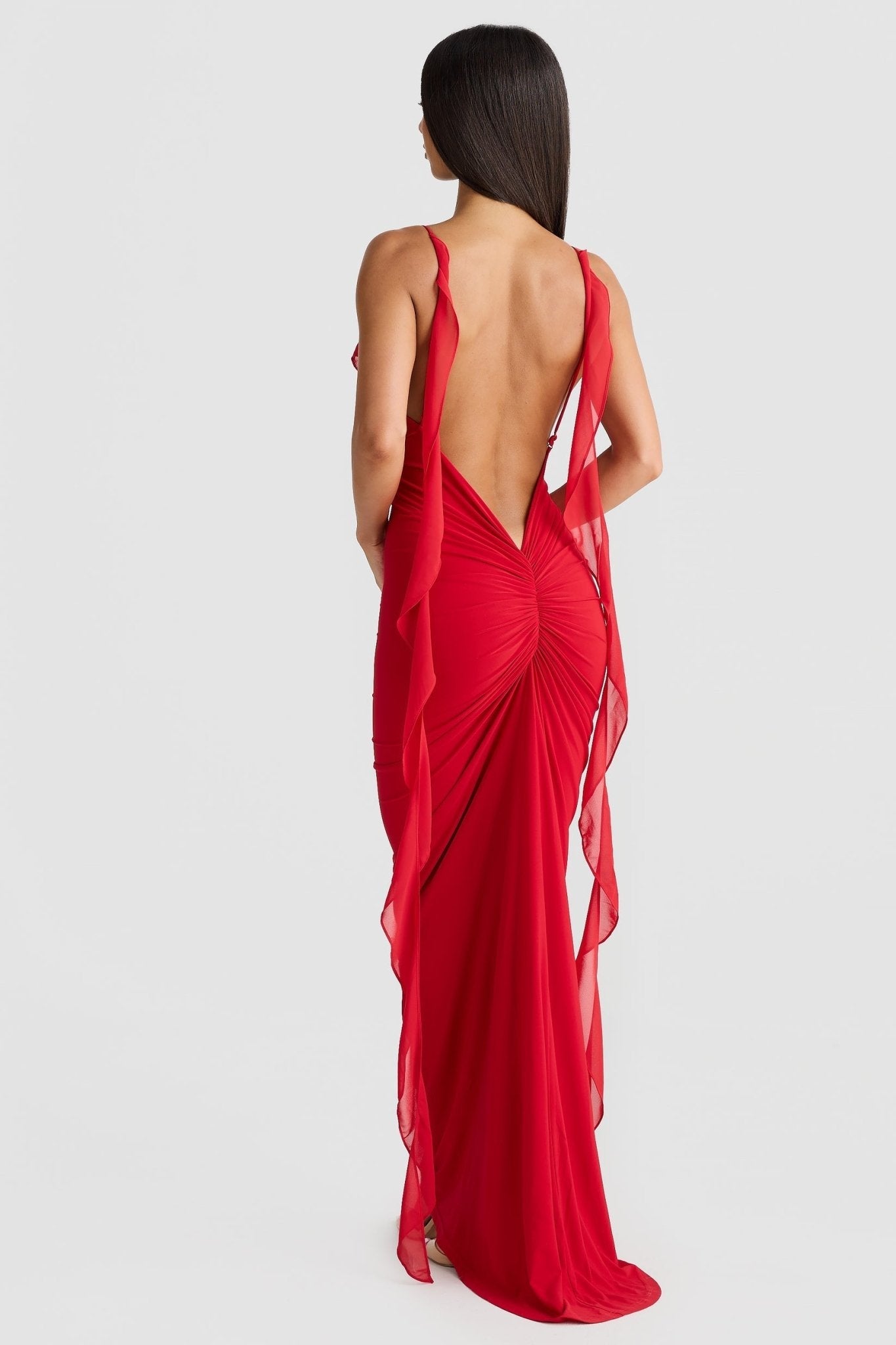 Back view of a red low back maxi dress, displaying the elegant open back and ruched skirt with flowing straps.