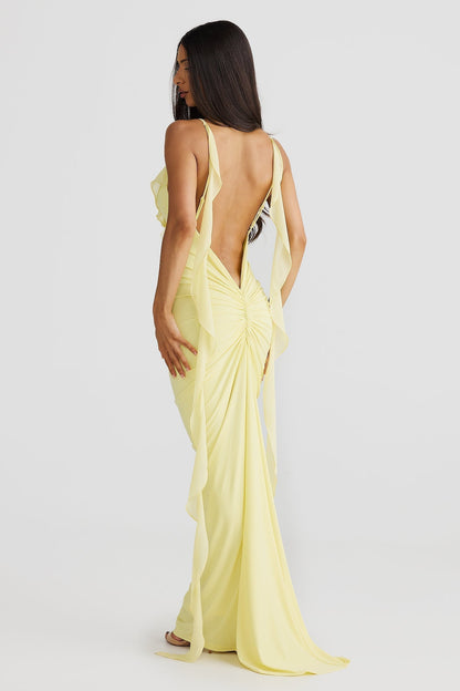 Back view of a yellow low back maxi dress featuring a ruched skirt and flowing straps, a beautiful vacation outfit.