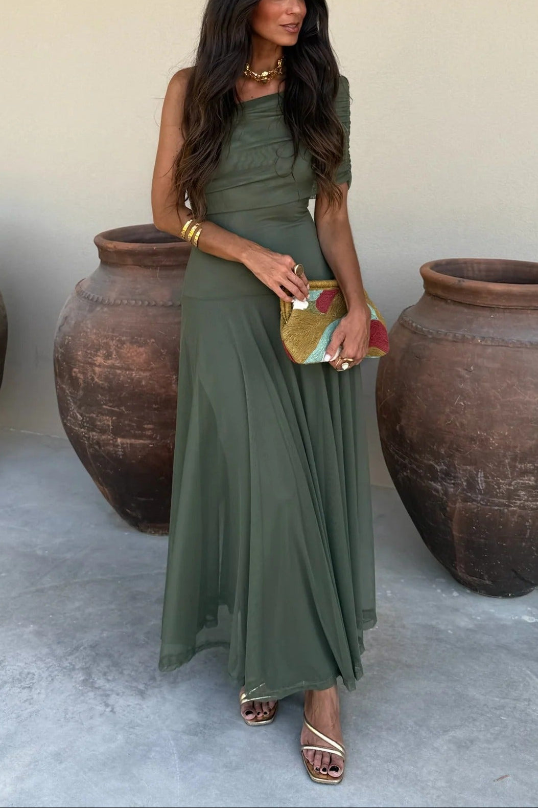 Women's off-shoulder draped mesh maxi dress in an olive green color, featuring a one-shoulder strap and a sheer, flowing skirt.