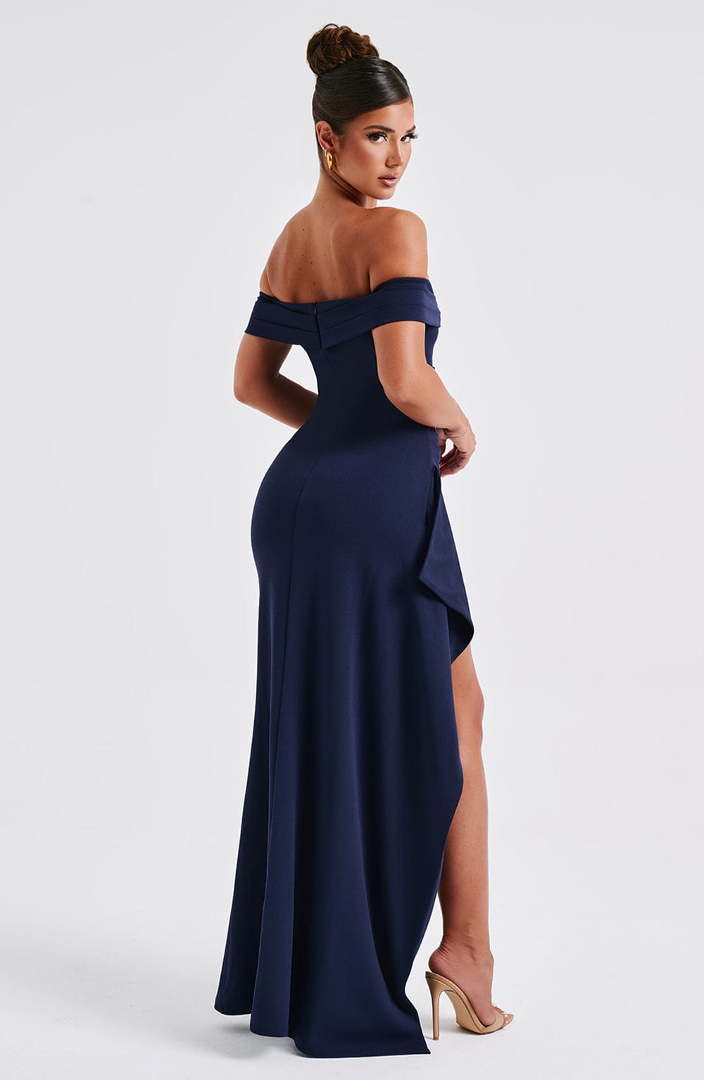 Angled back view of the navy blue off-shoulder pleated maxi dress, showing the high slit and form-fitting design.