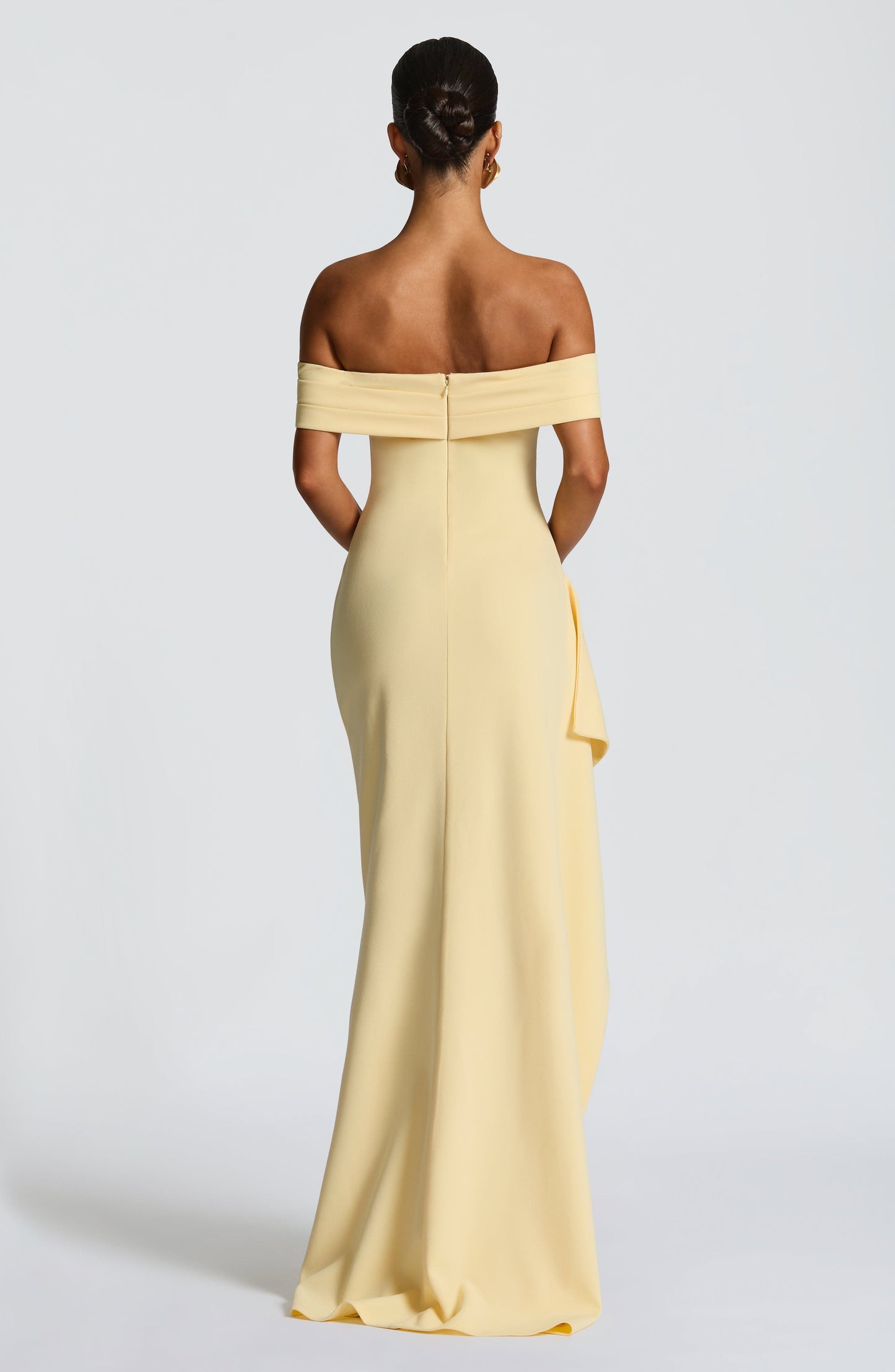 Back view of the light yellow off-shoulder pleated maxi dress, highlighting the fitted silhouette and back zipper.