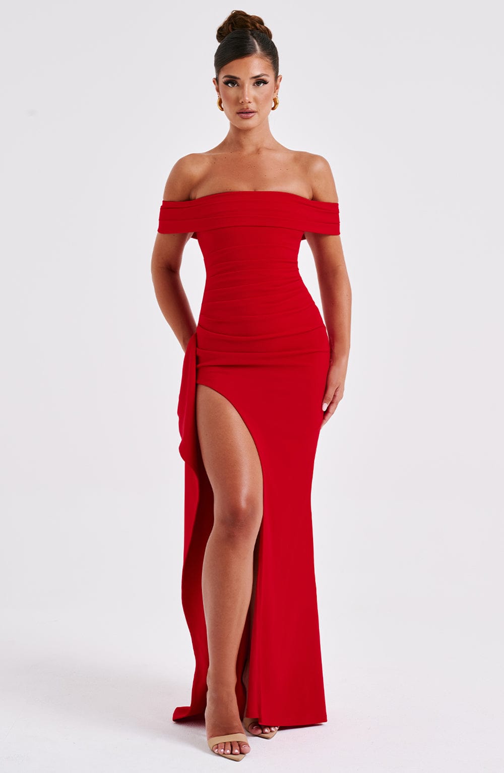Full length view of a vibrant red off-shoulder pleated maxi dress with a high slit and ruched bodice.