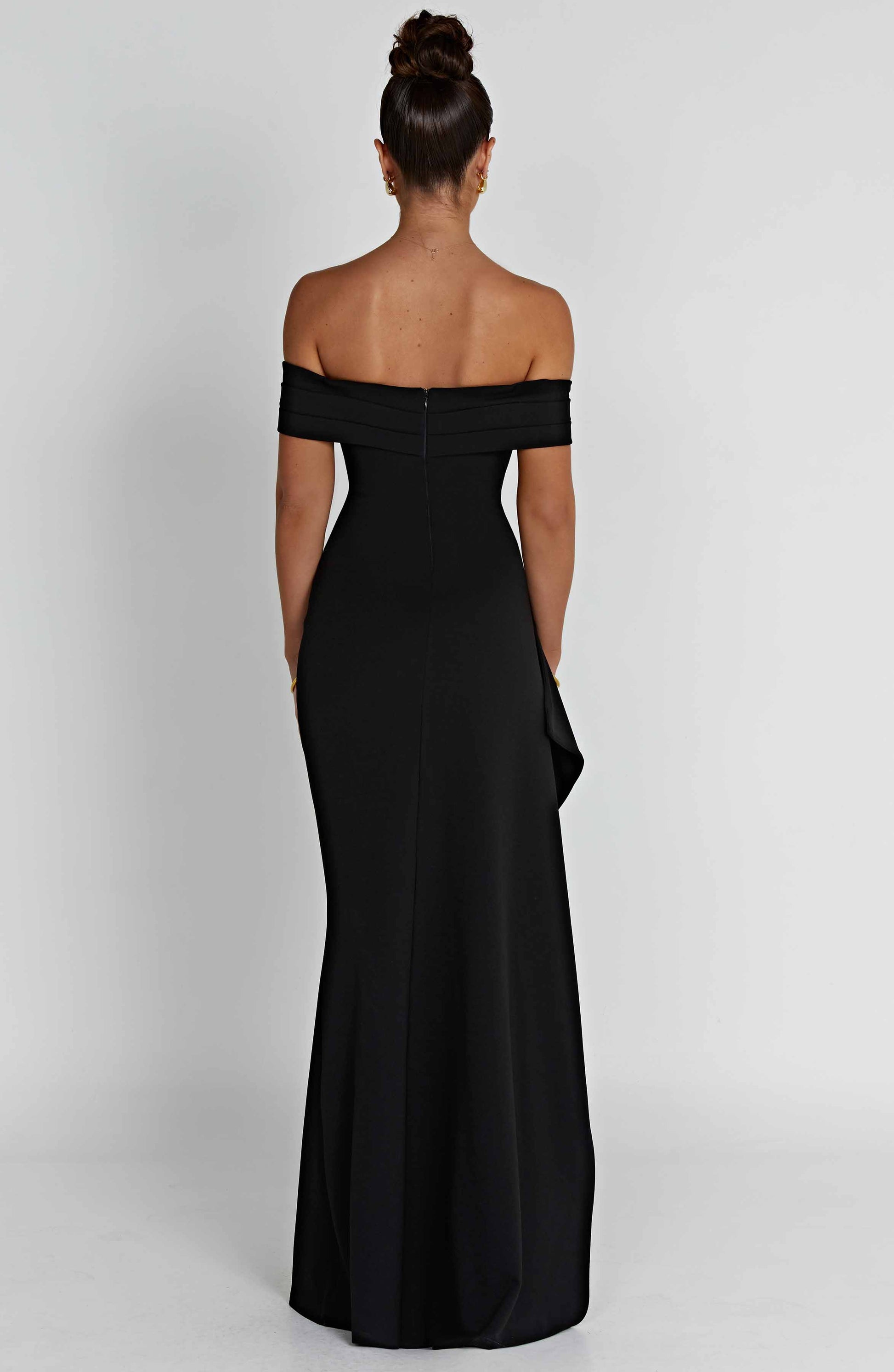 Back view of the black off-shoulder pleated maxi dress, showing the smooth fabric and back zipper detail.