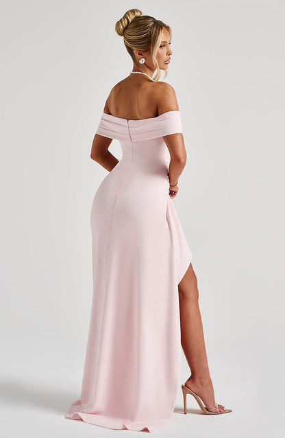 Back angled view of the pink off-shoulder pleated maxi dress, showcasing the high slit and flowing skirt.