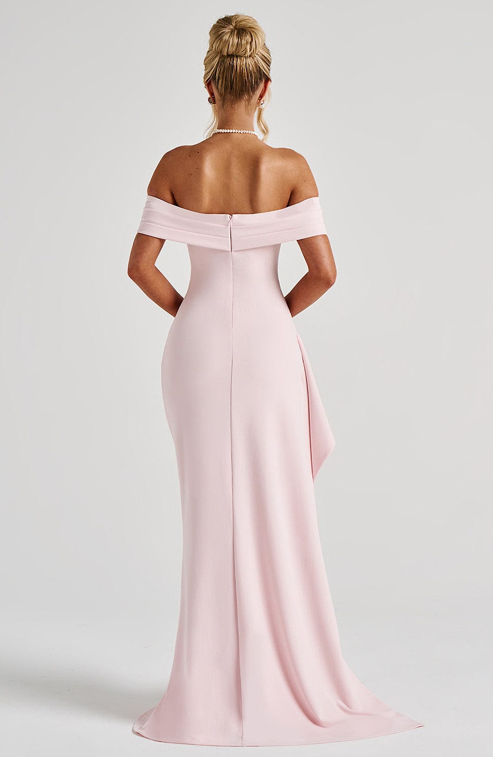 Rear view of the light pink off-shoulder pleated maxi dress, highlighting the fitted bodice and long skirt.