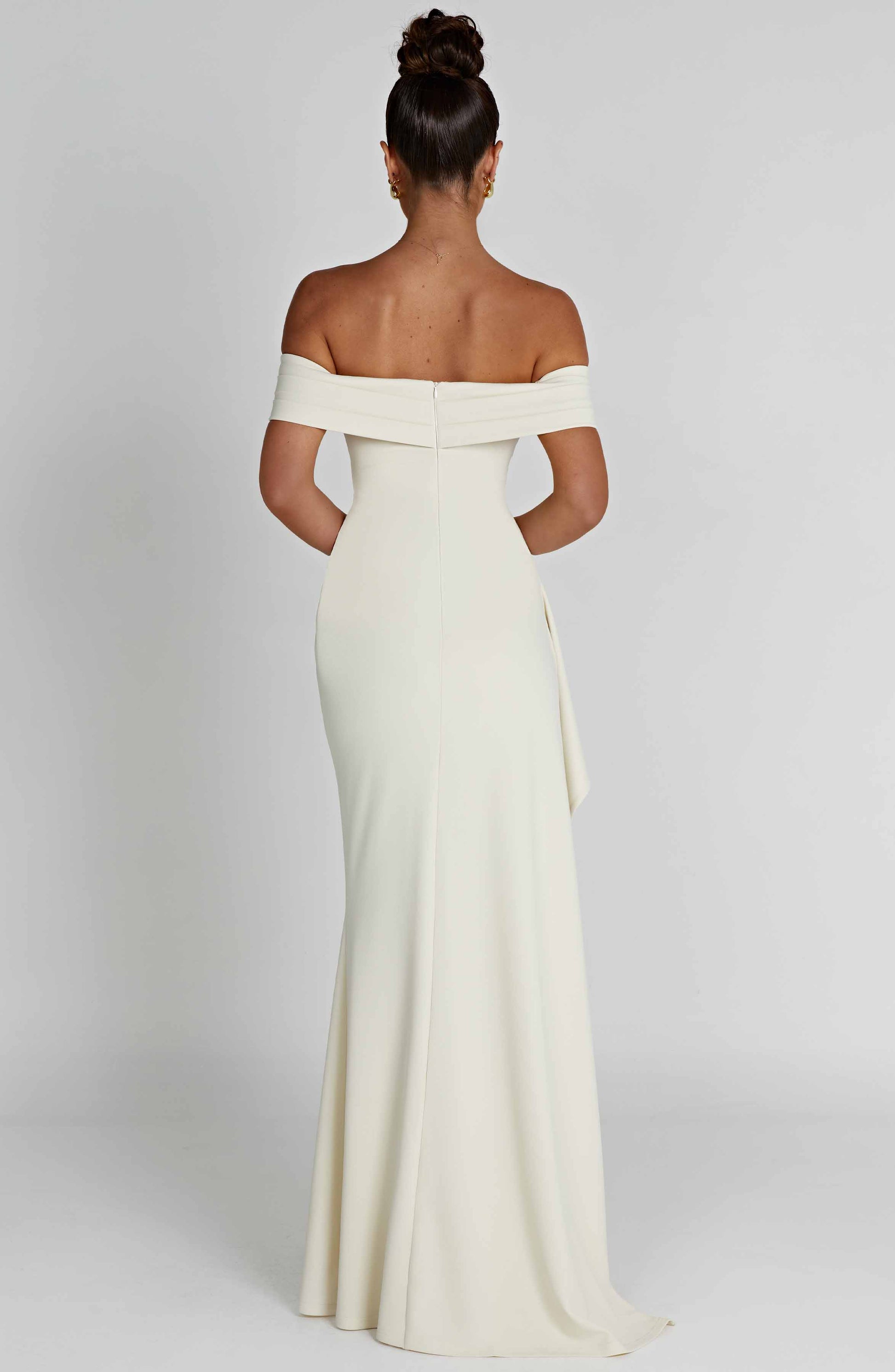Back view of the white off-shoulder pleated maxi dress, revealing the fitted silhouette and floor-length hem.