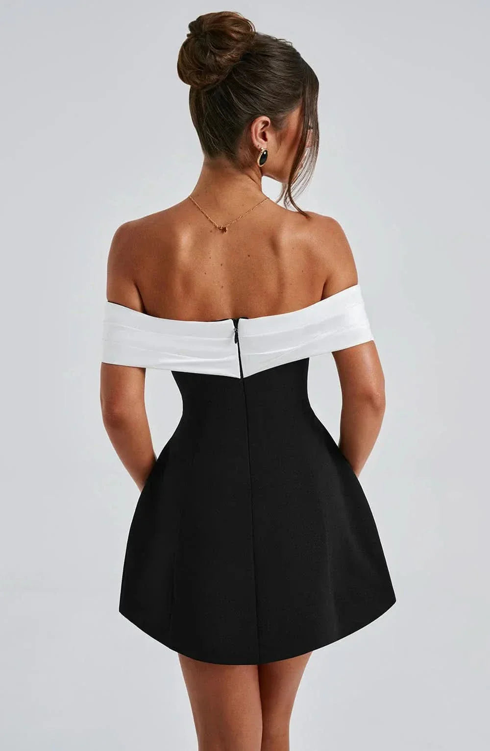 Back view of women's black off-shoulder mini dress, showing the zipper closure without the detachable bow.