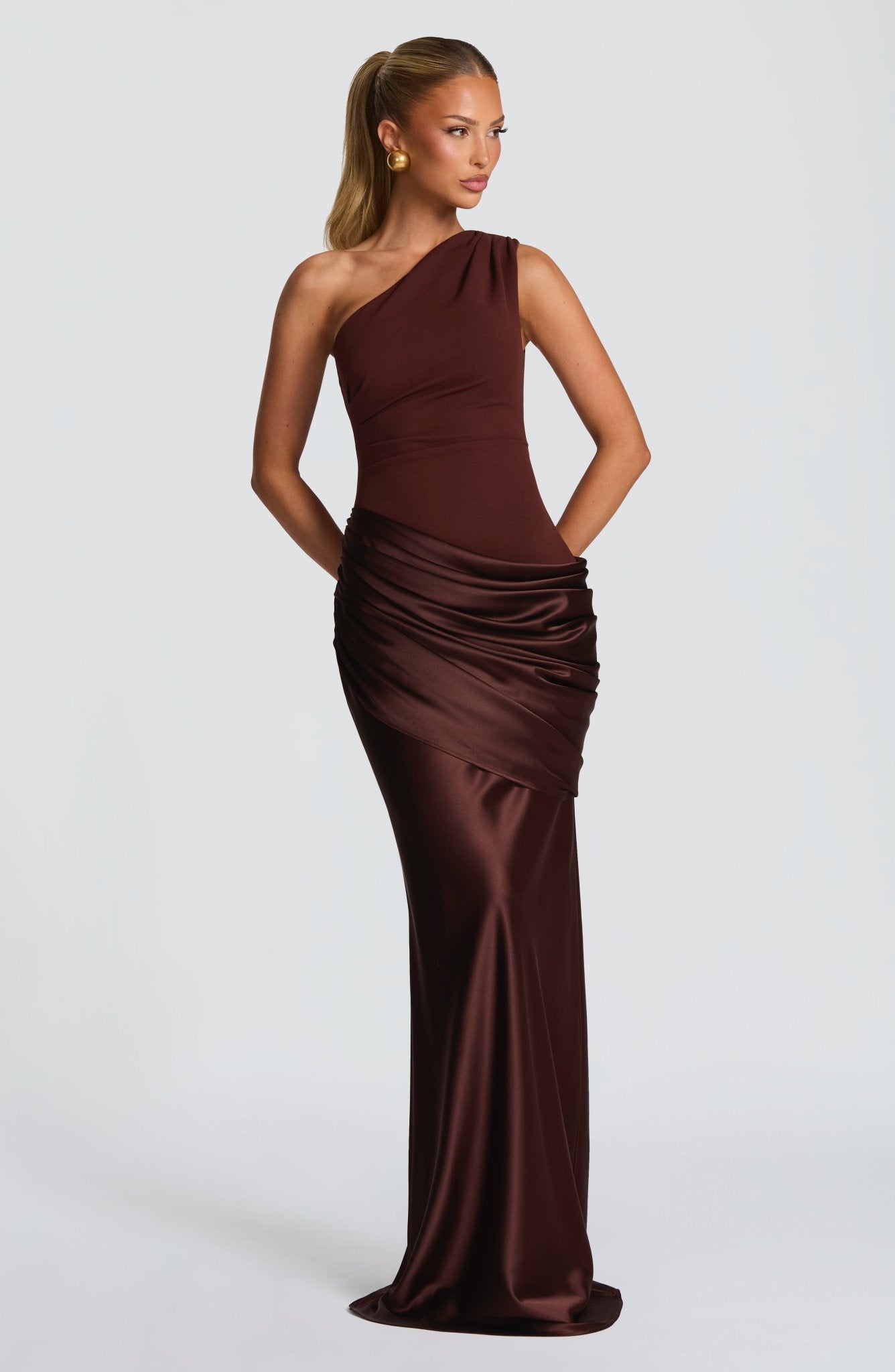 Front view of a women's dark brown one-shoulder draped formal maxi dress, showcasing the fitted bodice and flowing skirt.