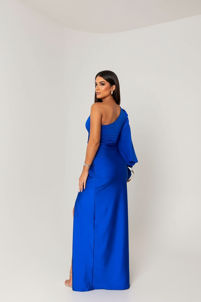 Back view of the royal blue one-shoulder maxi dress, displaying the flowing skirt and single sleeve.