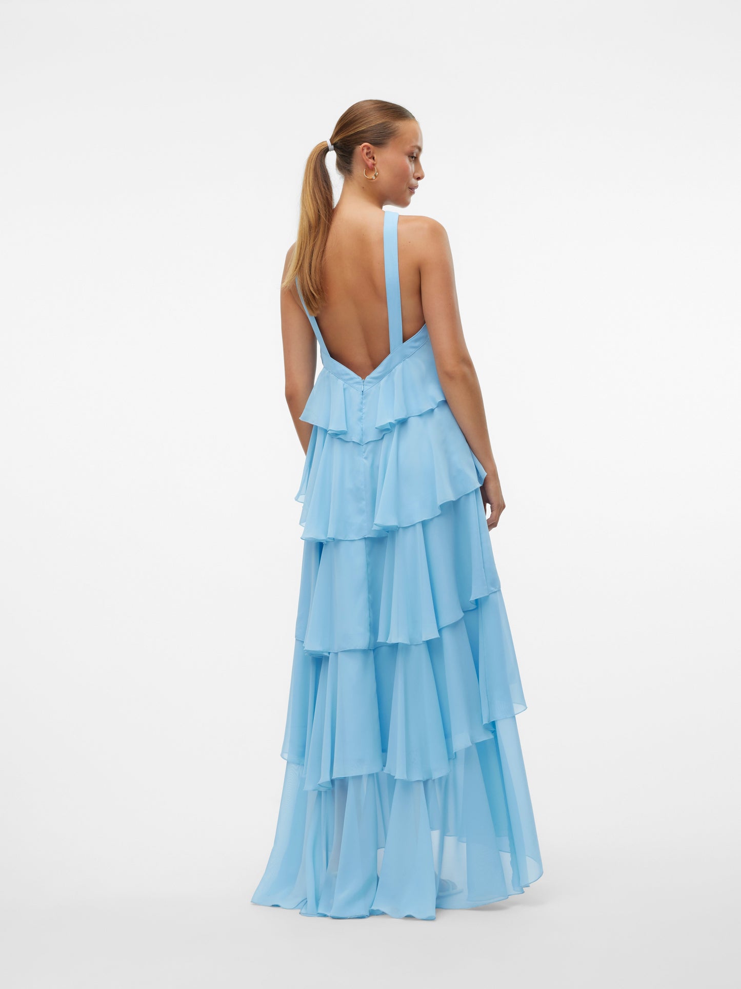 Front view of a woman wearing a light blue ruffled halter neck maxi dress with an open back, suitable for parties or as a vacation dress.
