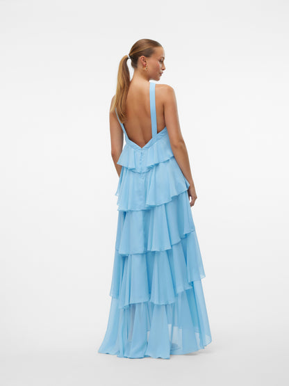 Front view of a woman wearing a light blue ruffled halter neck maxi dress with an open back, suitable for parties or as a vacation dress.