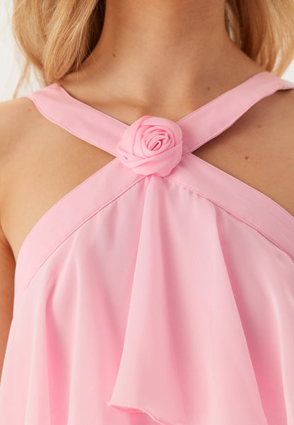 Detail shot of the halter neckline of the pink maxi dress, featuring a delicate rose embellishment.