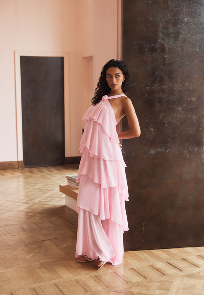 Back view of a light pink halter ruffle maxi dress, showcasing the open back and flowing tiered skirt.