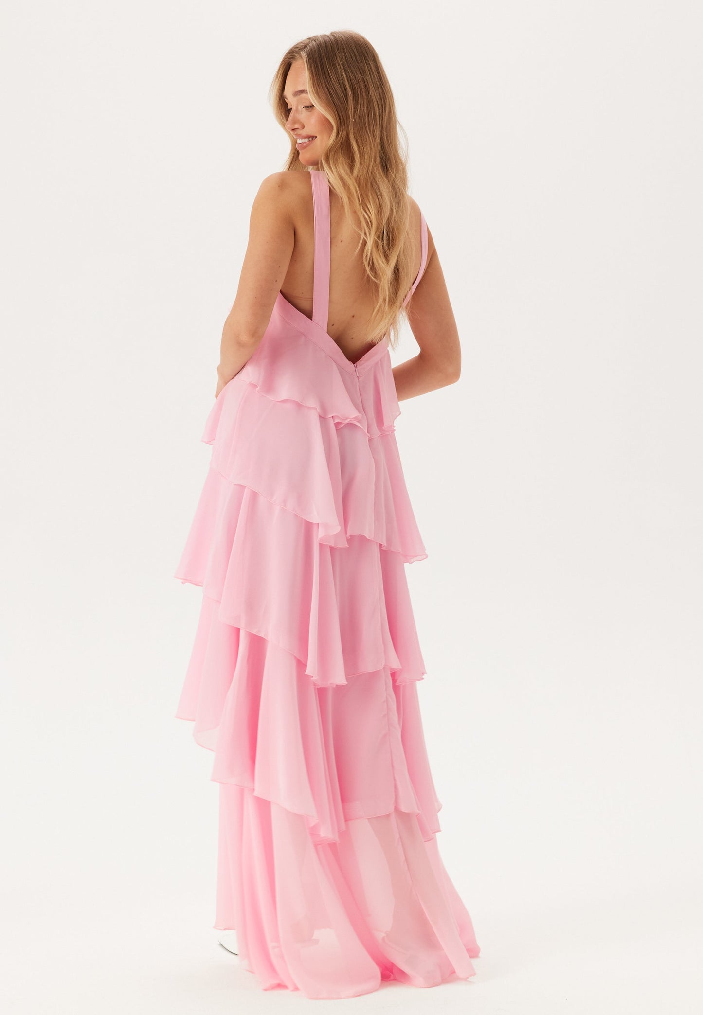 Back view of a pink tiered ruffle maxi dress, highlighting the low back and delicate halter straps.