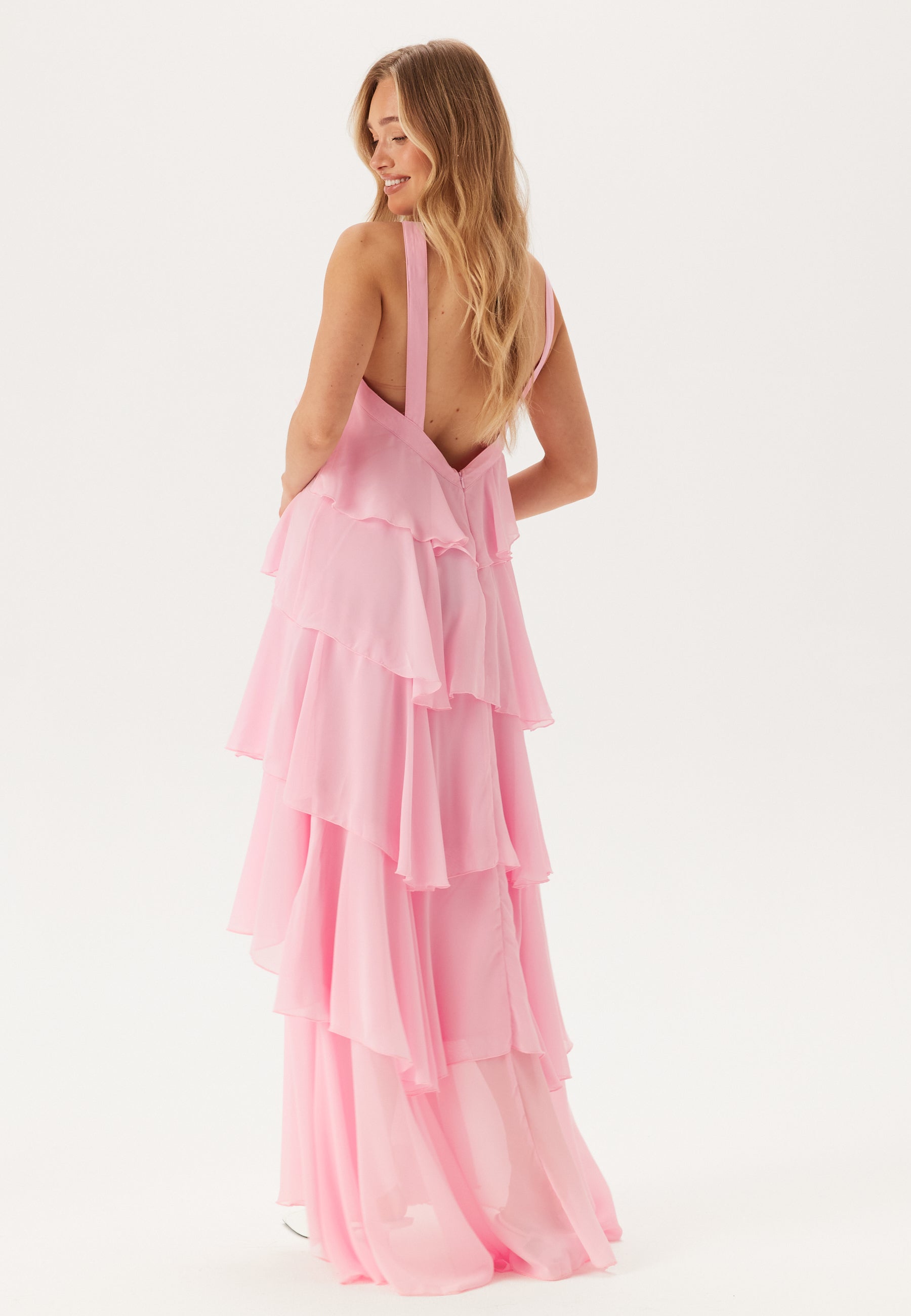 Back view of a pink tiered ruffle maxi dress, highlighting the low back and delicate halter straps.