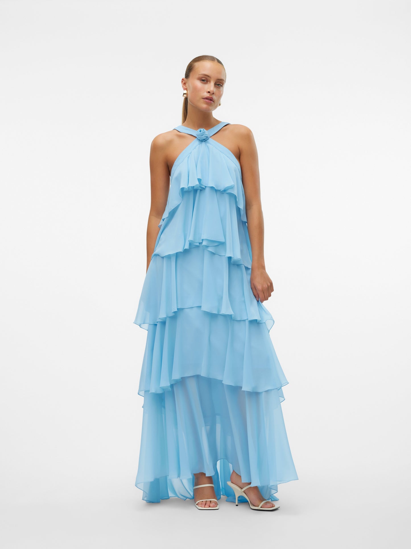Woman posing with hand on hip, wearing a light blue ruffled halter neck maxi dress with an open back, ideal for summer parties or vacation outfits.