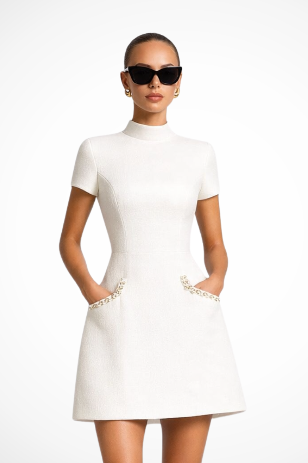 White pearl trim mock neck mini dress with short sleeves and decorative front pockets, front view.