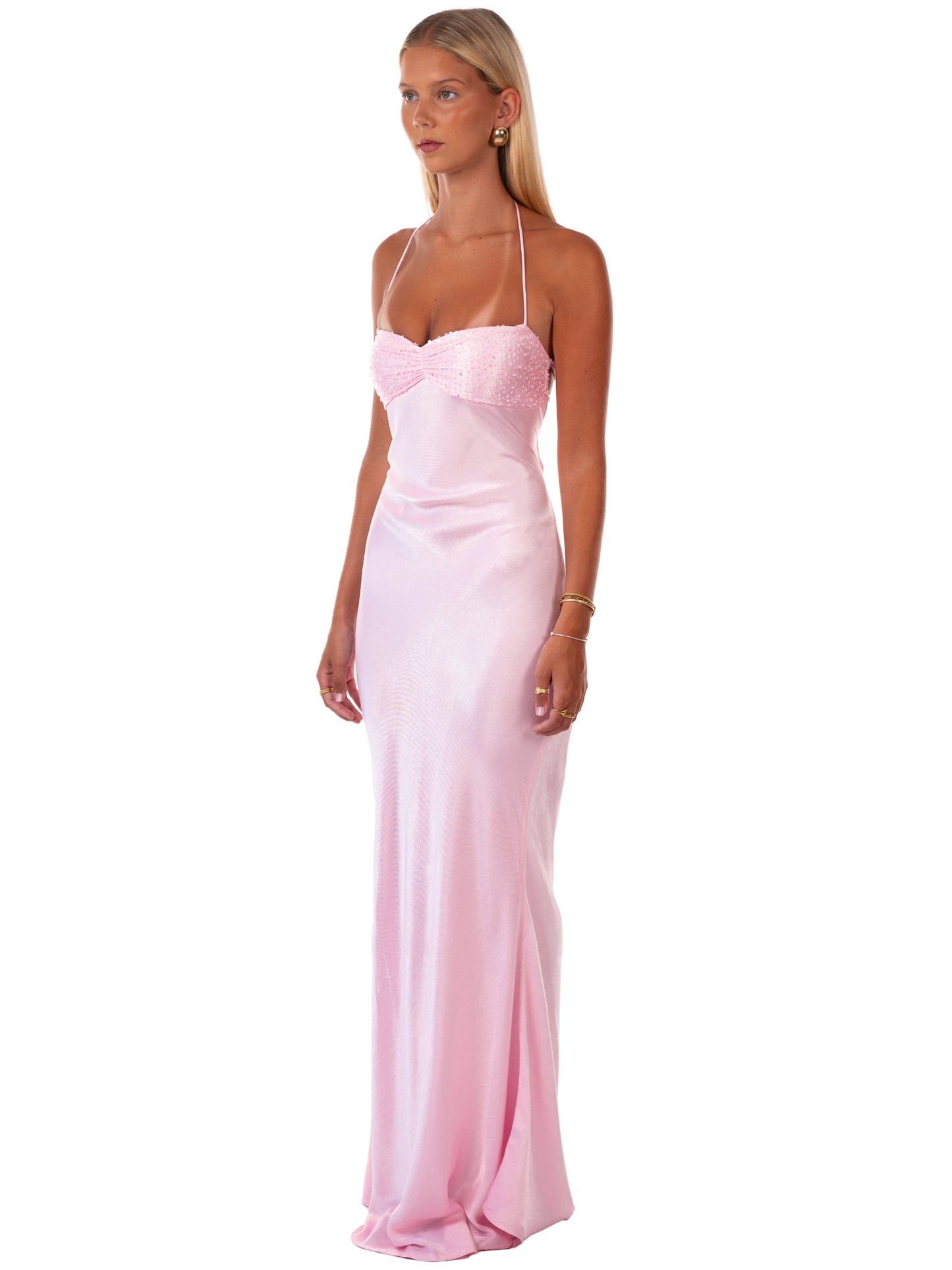 Three-quarter view of a women's pink sequin halter neck backless maxi dress, showing the satin fabric.