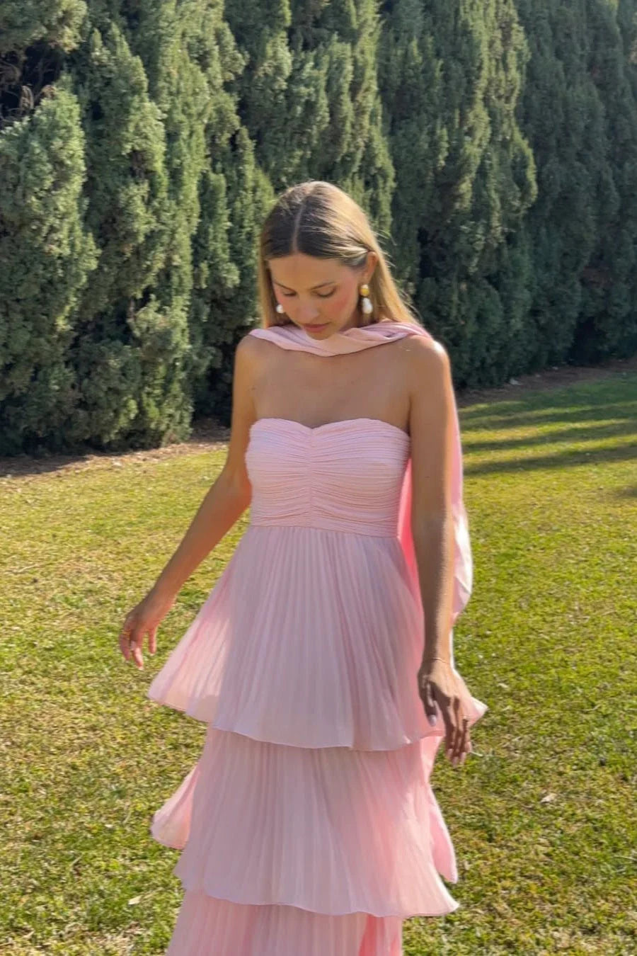 Light pink strapless tiered maxi dress with pleated skirt and flowing scarf detail, perfect for vacation outfits