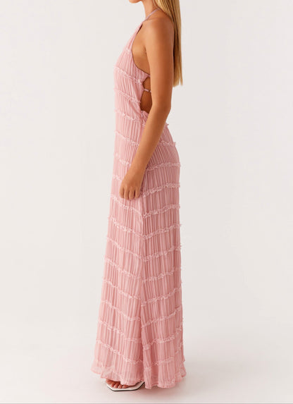 Side view of blush pink halter maxi dress showing open sides, pleats, and ruffle hem