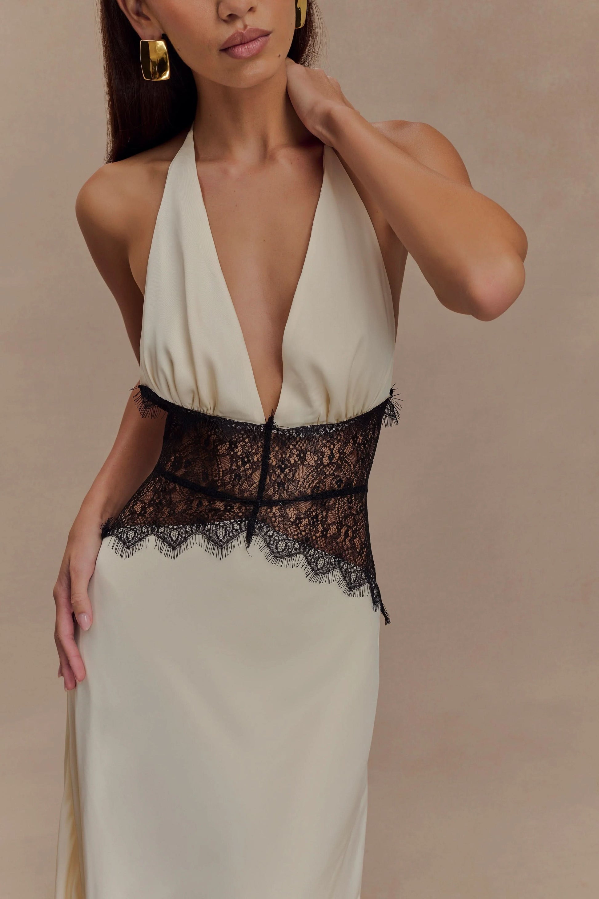 Close-up front view of a women's cream halter V neck maxi dress, detailing the black lace bodice and deep V neckline.