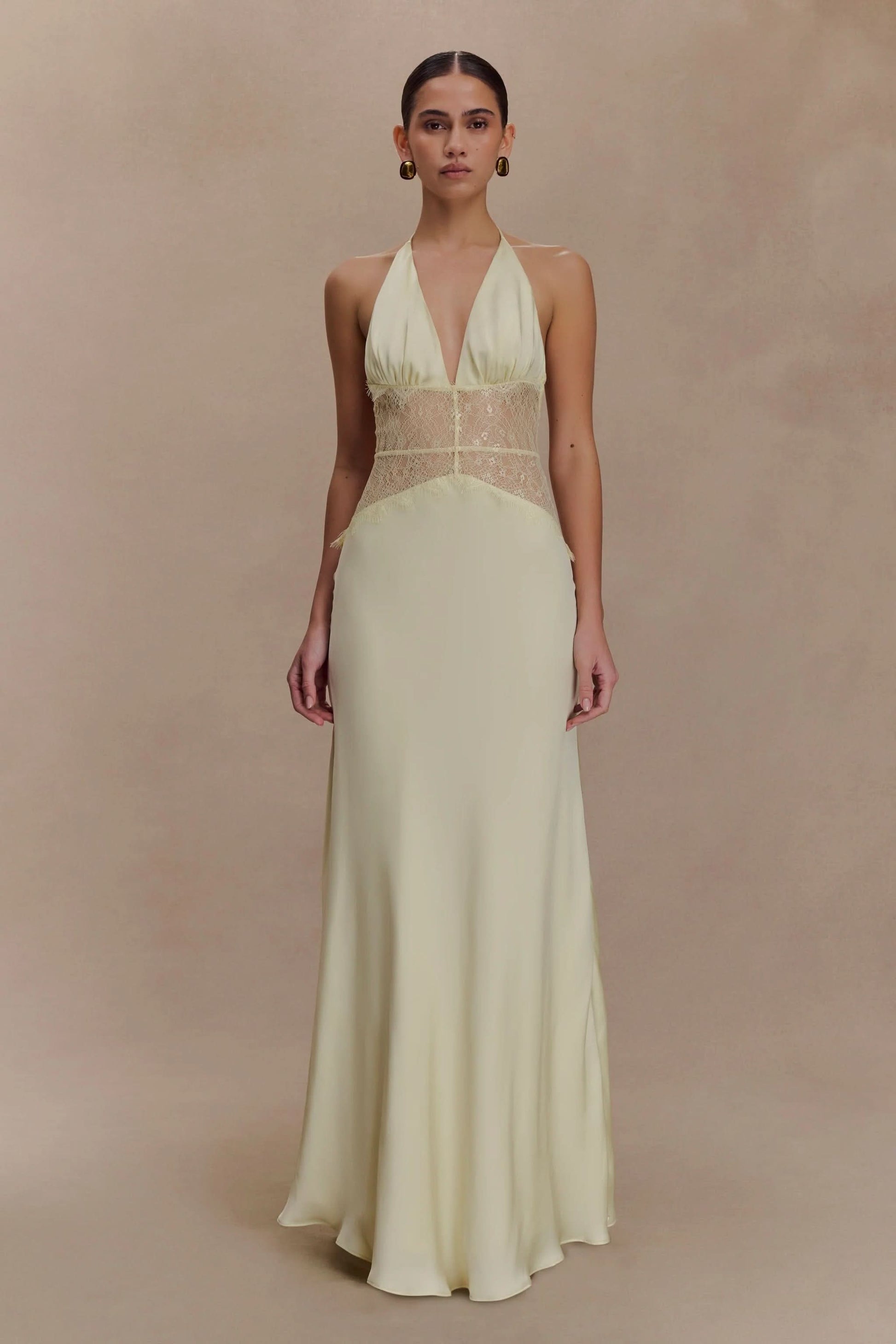Front view of a women's pale yellow halter V-neck maxi dress with delicate lace details on the bodice, perfect for vacation outfits.