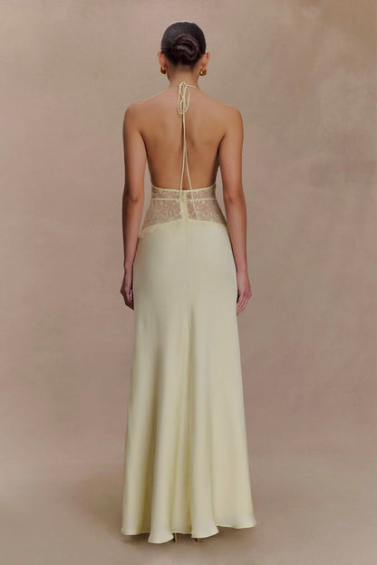 Back view of a women's pale yellow halter V-neck maxi dress, showcasing the open back and lace details, an elegant dress for wedding guests.