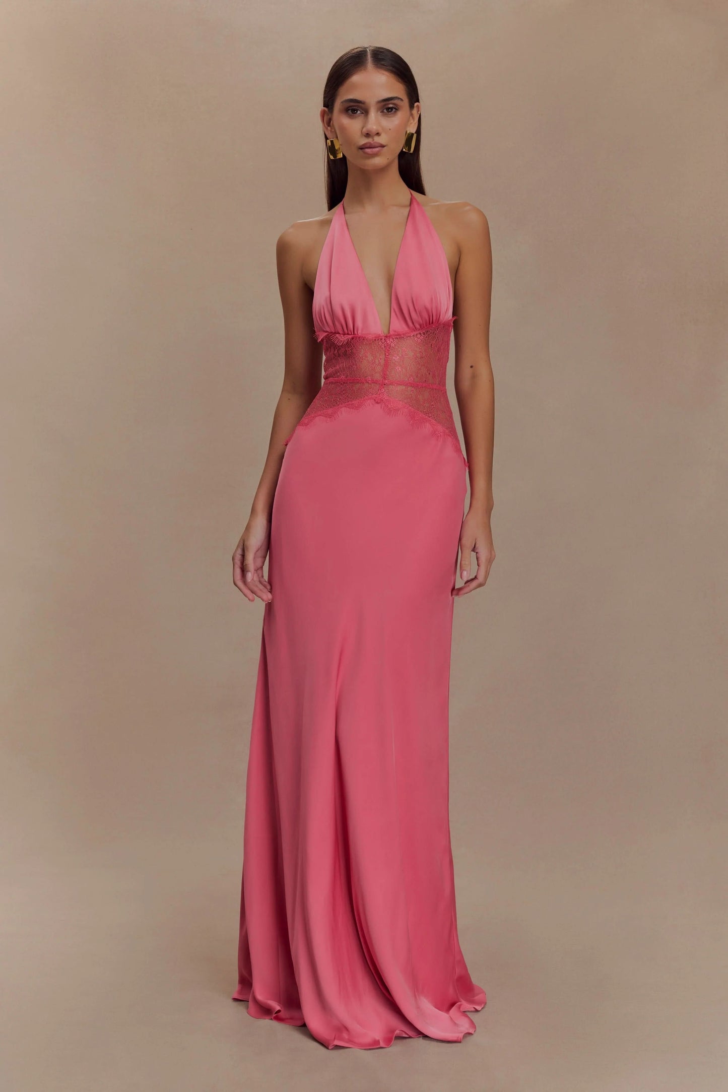 Front view of a women's vibrant pink halter V-neck maxi dress with sheer lace panels on the midriff, a stunning vacation dress.