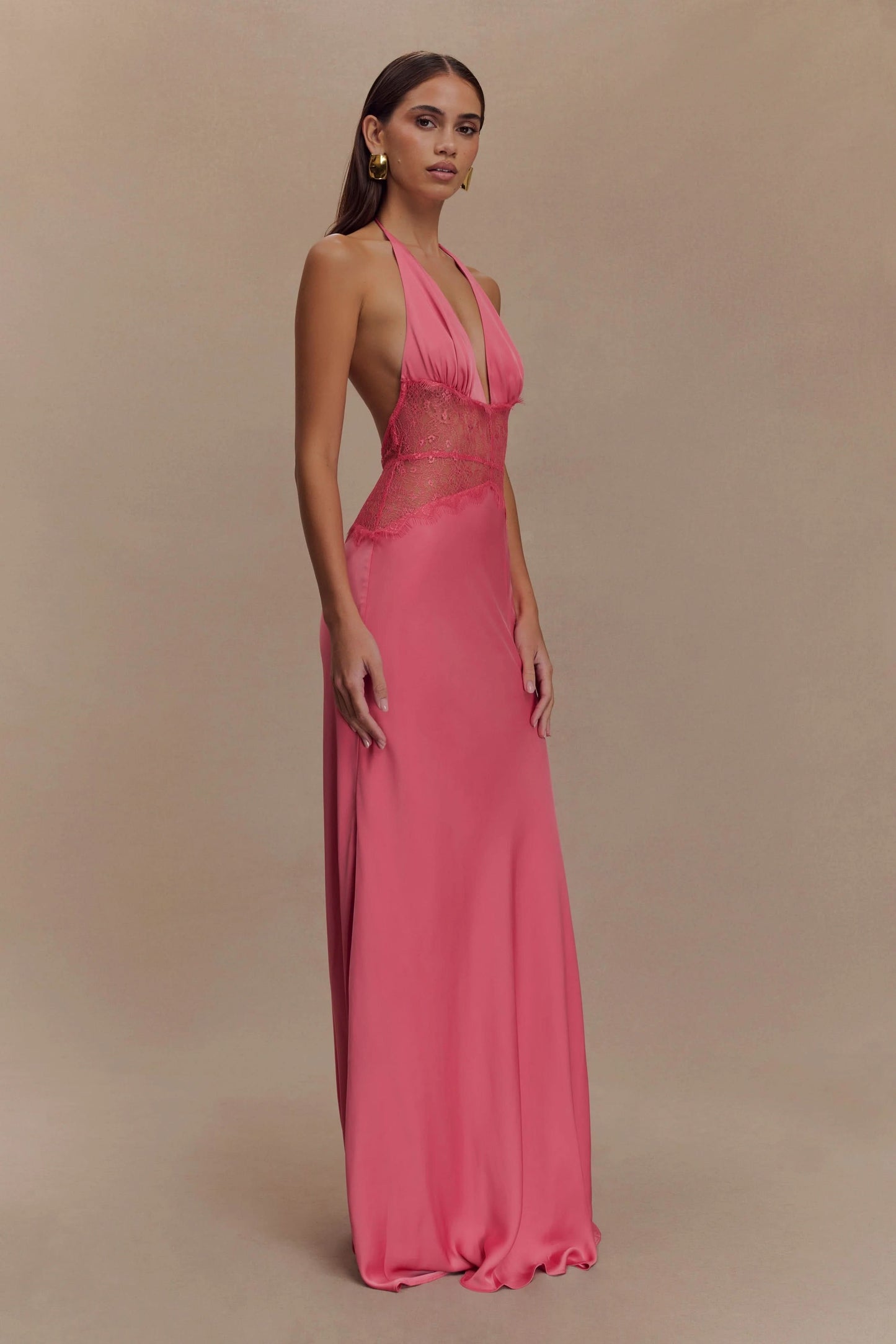 Side view of a women's vibrant pink halter V-neck maxi dress, showing the flowing silhouette and deep V neckline, ideal for wedding guest dresses.