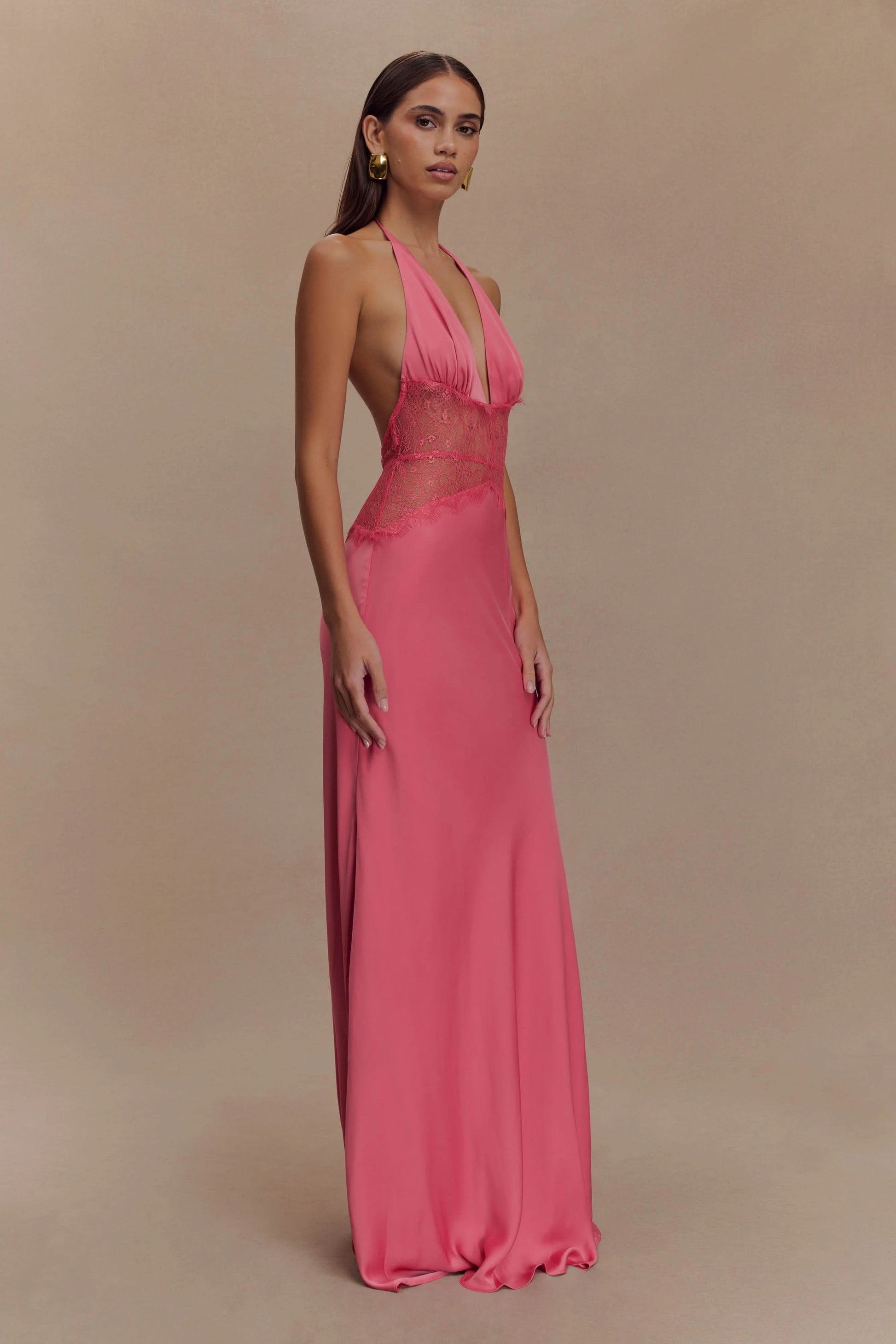 Side view of a women's vibrant pink halter V-neck maxi dress, showing the flowing silhouette and deep V neckline, ideal for wedding guest dresses.