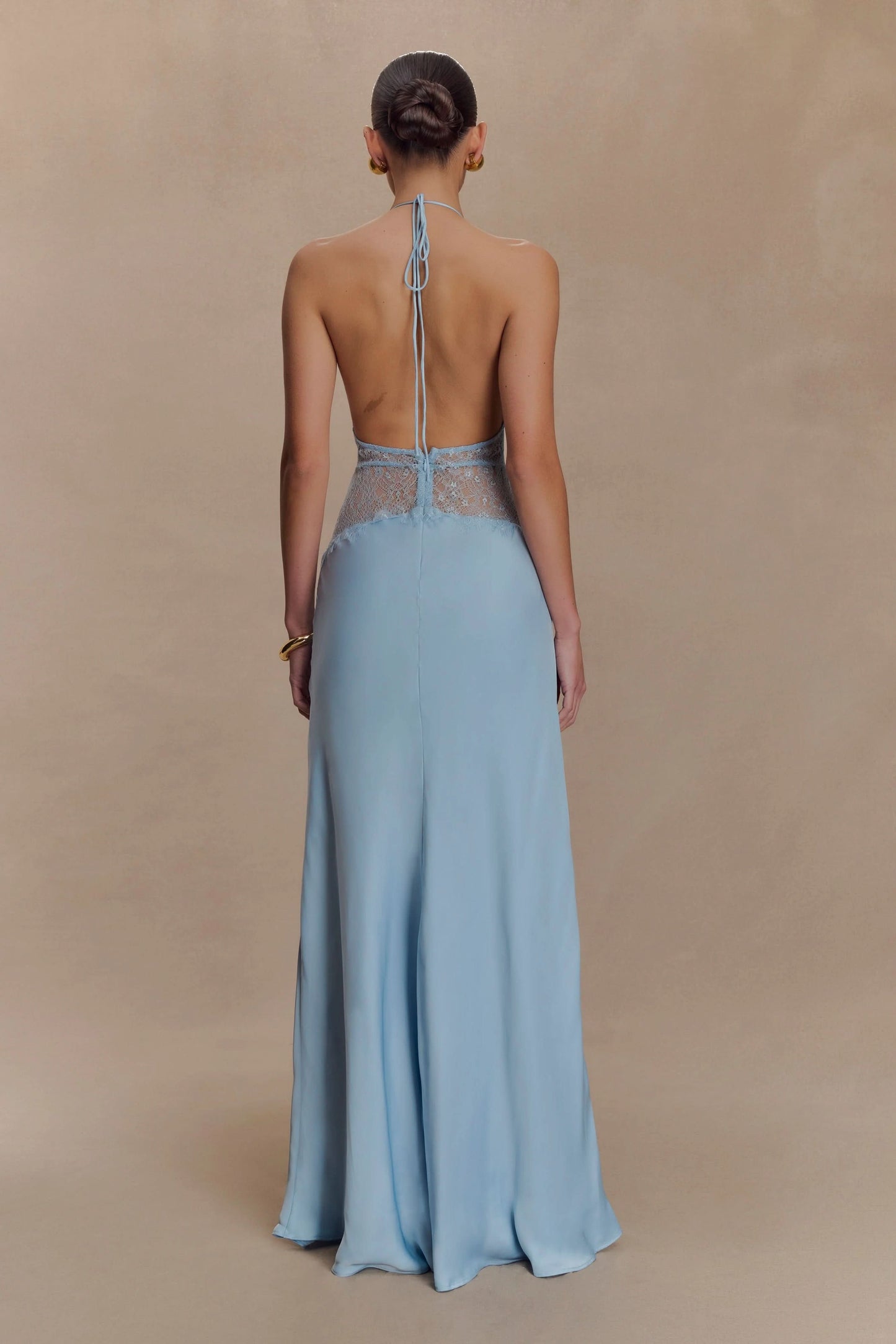 Back view of a women's light blue halter V-neck maxi dress, highlighting the open back and lace panel, a sophisticated choice for wedding guests.