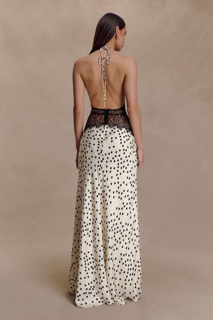 Back view of a women's cream polka dot halter V neck maxi dress with black lace bodice and open back design.