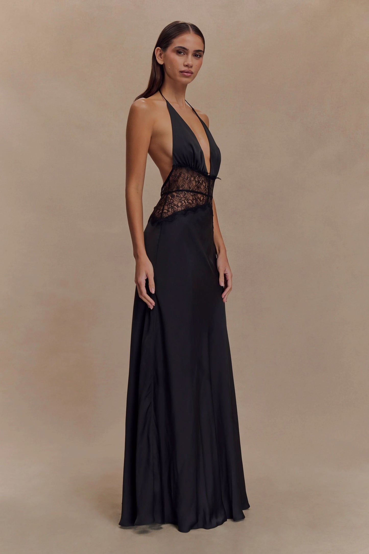Side view of a women's black halter V neck maxi dress, showcasing the black lace bodice and flowing skirt.