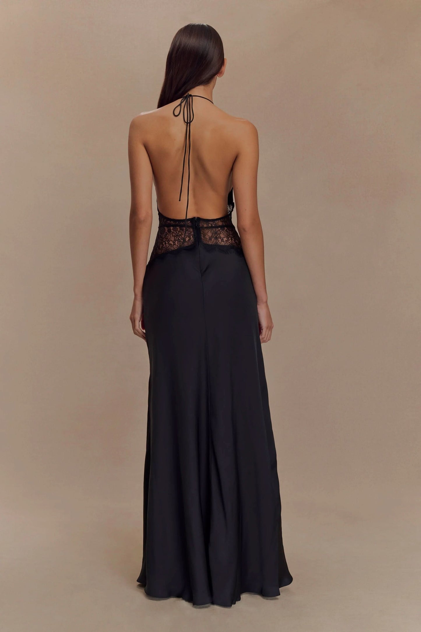 Back view of a women's black halter V neck maxi dress, featuring a black lace bodice and open back design.