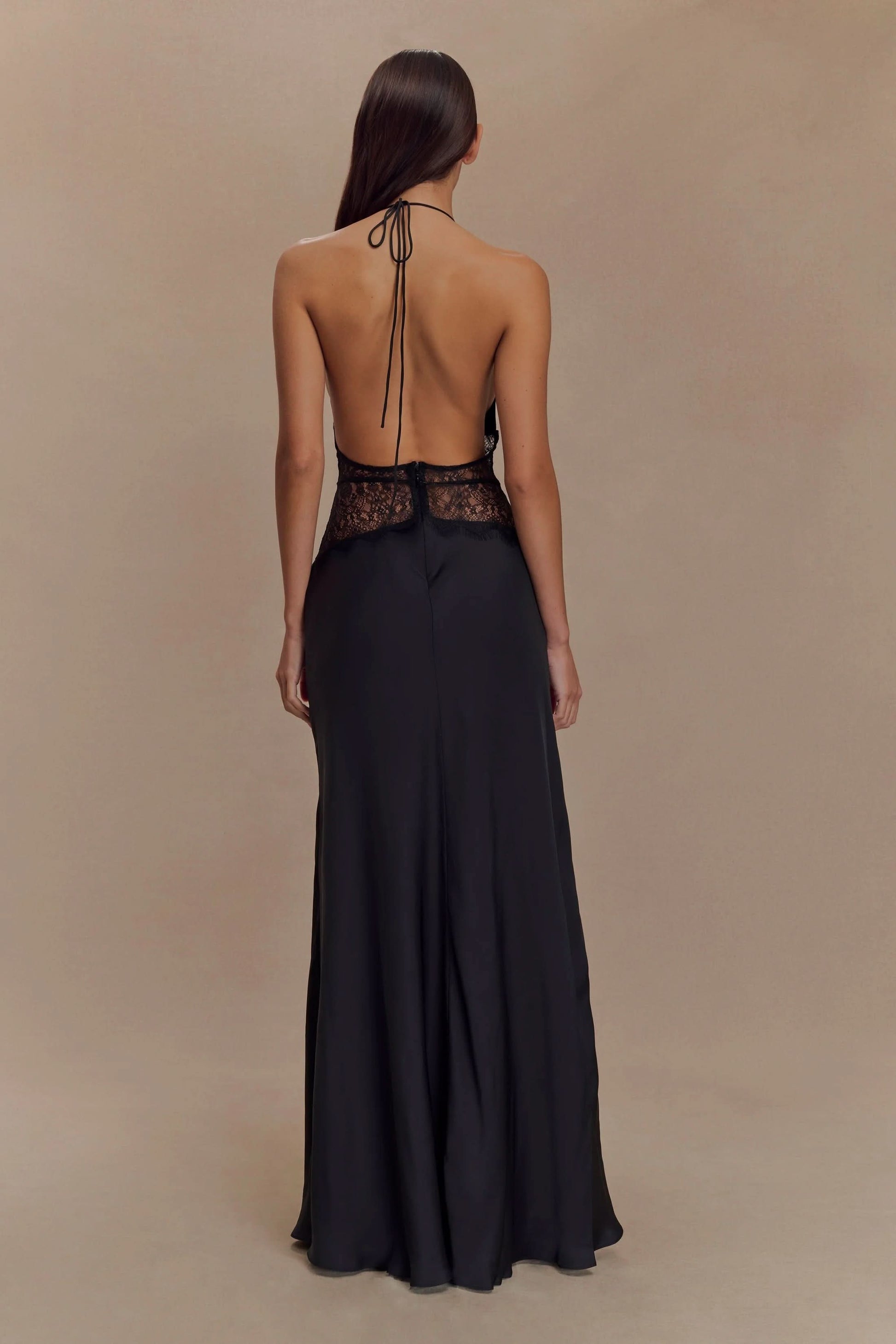 Back view of a women's black halter V neck maxi dress, featuring a black lace bodice and open back design.