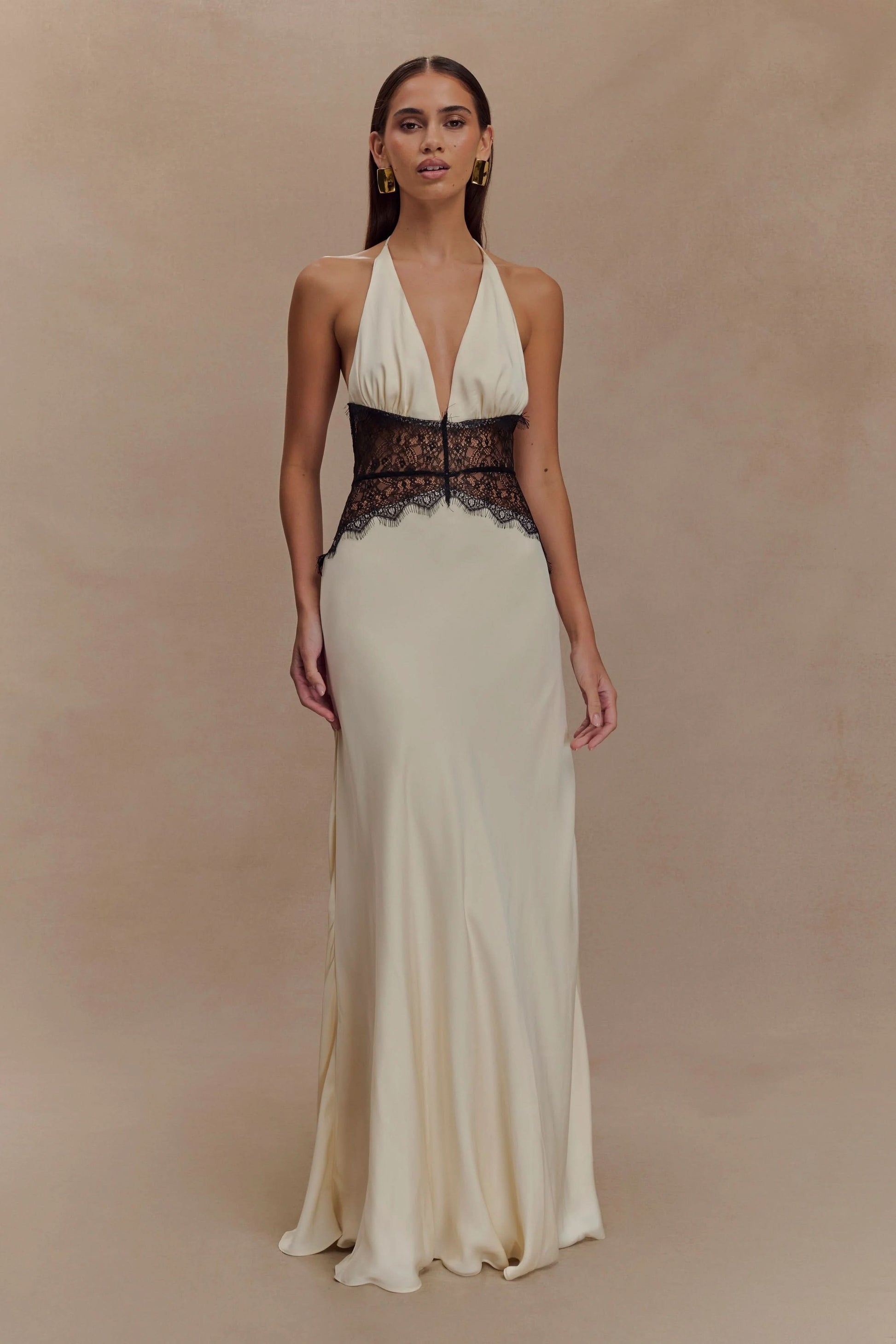 Front view of a women's cream halter V neck maxi dress with black lace bodice detail, a sophisticated vacation dress.