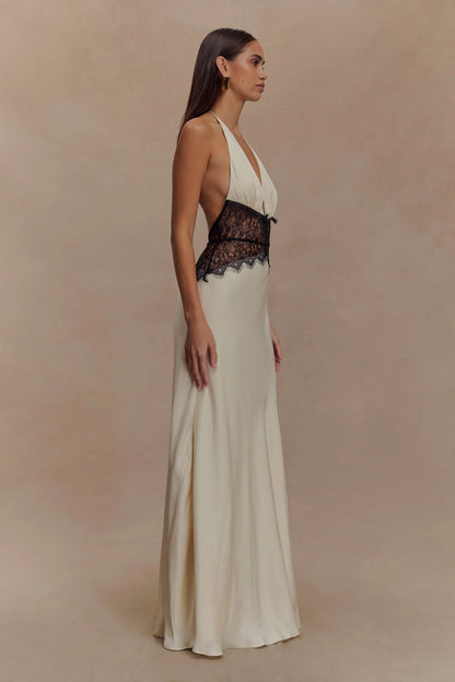 Side view of a women's cream halter V neck maxi dress, highlighting the black lace bodice and long skirt.