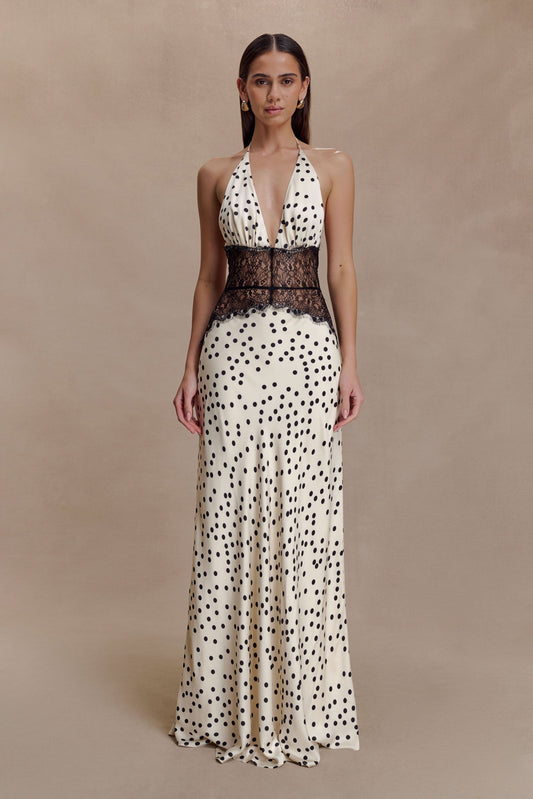 Front view of a women's halter V neck maxi dress in cream with black polka dots and black lace bodice detail.