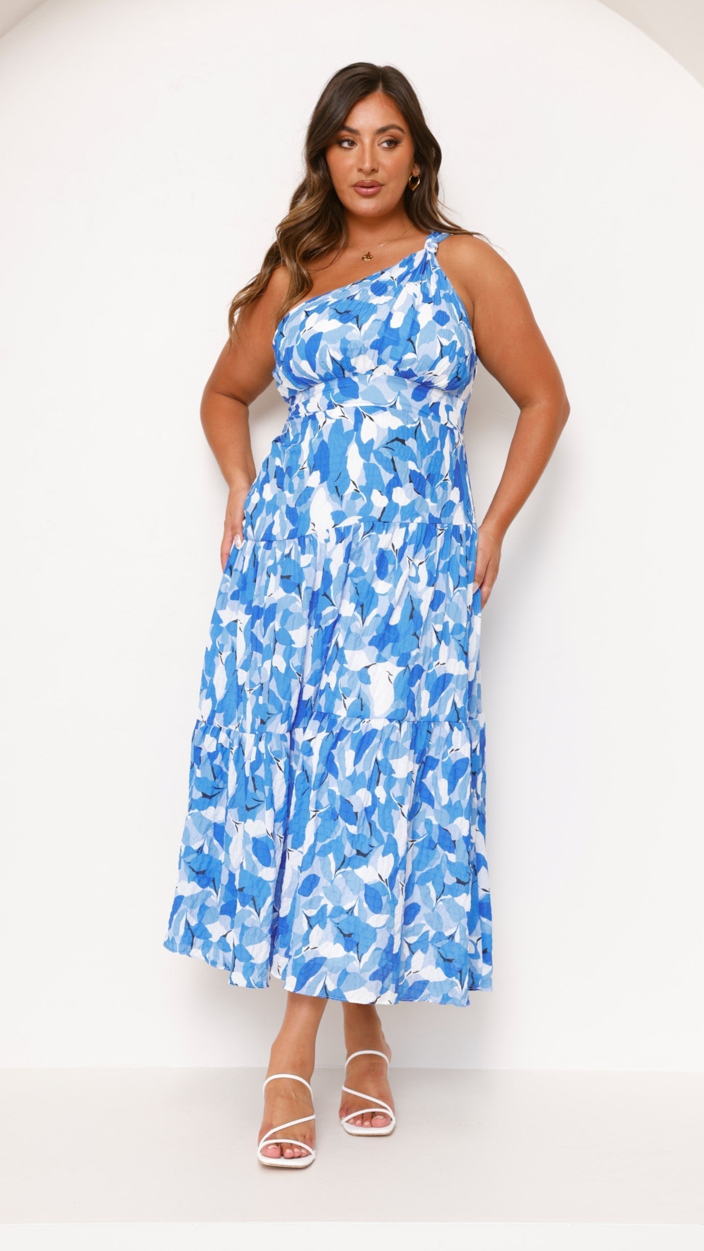 Plus size women's one-shoulder midi dress in a vibrant blue and white abstract print with a tiered skirt.