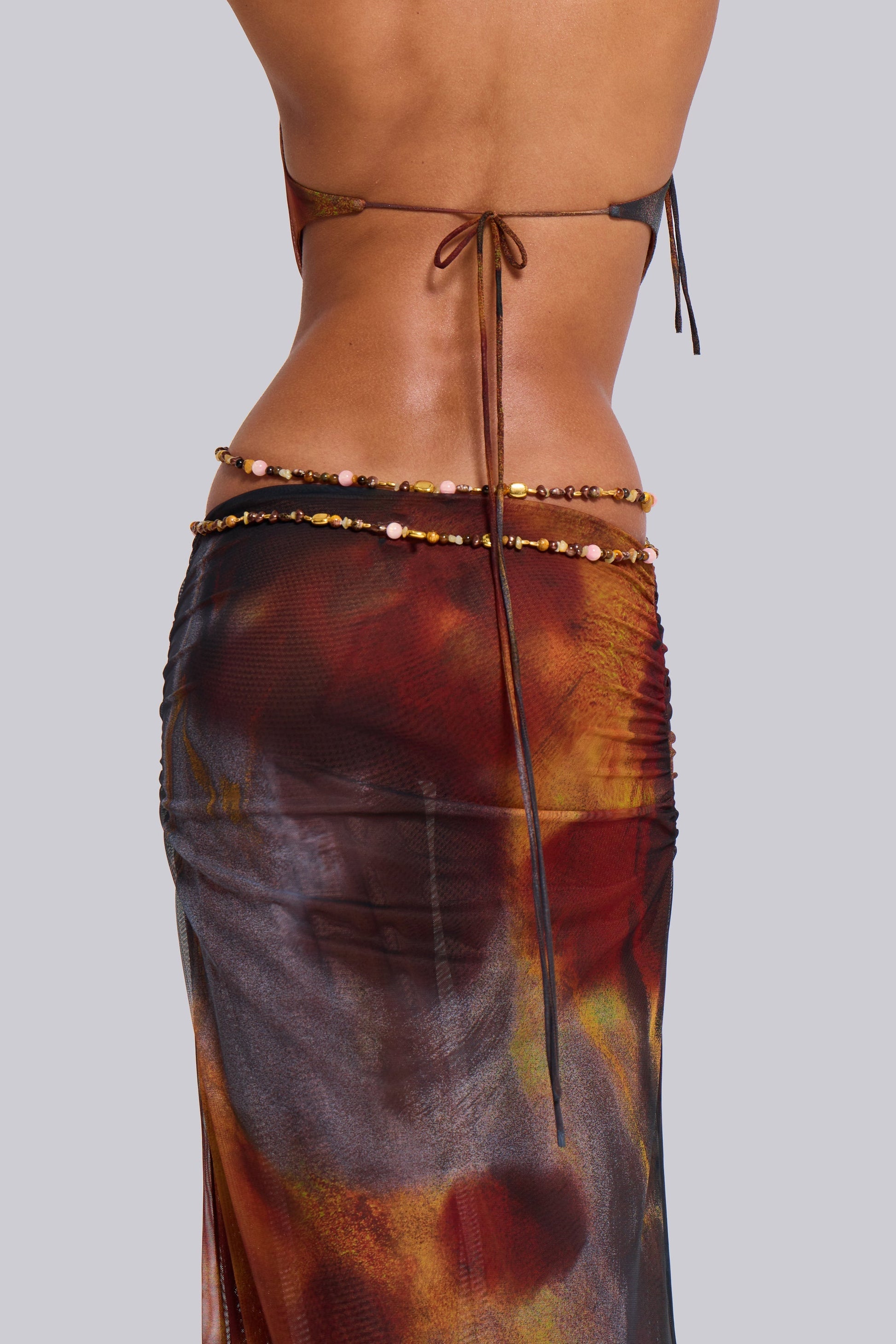 Back close-up of the waist and lower back of the printed halter maxi dress, showing the tie closure and beaded waist chain.