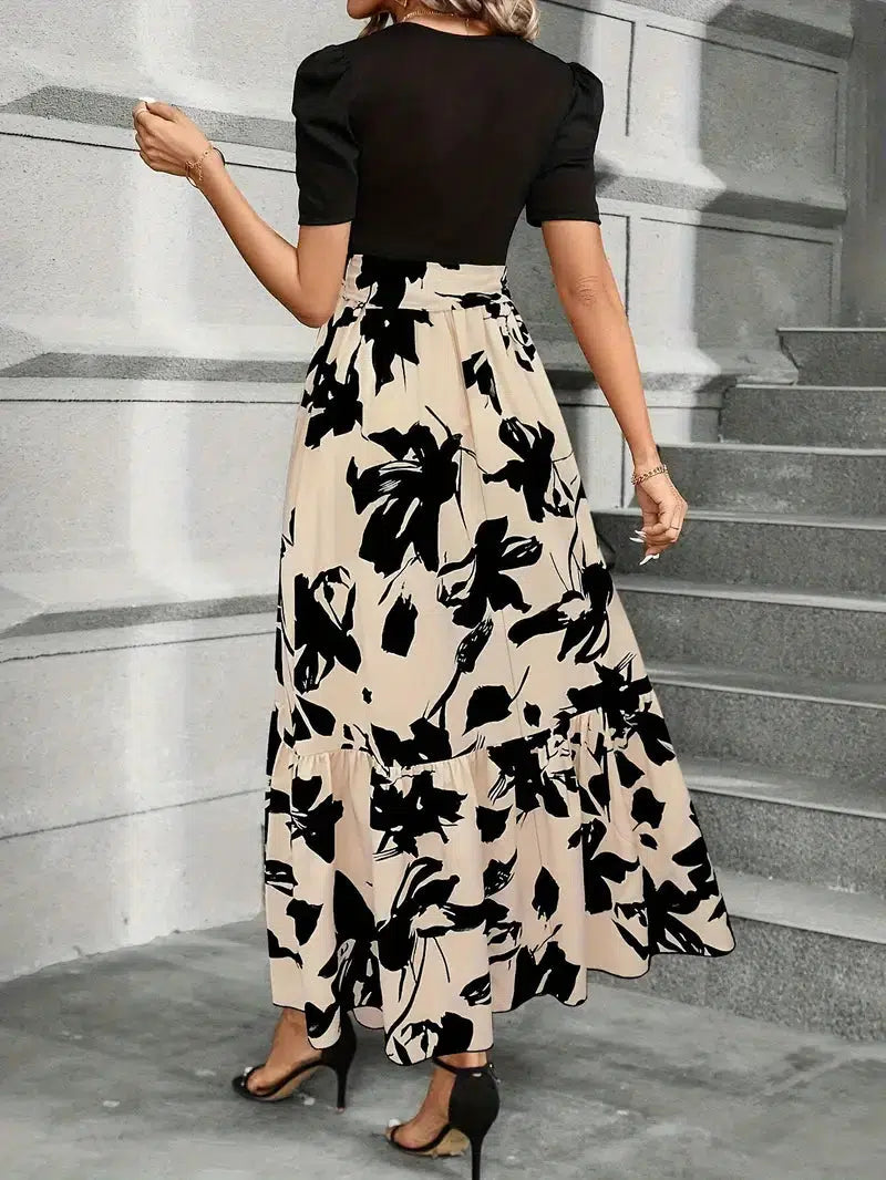 Back view of women's black and beige floral printed maxi dress with puff sleeves, showcasing the flowing skirt.