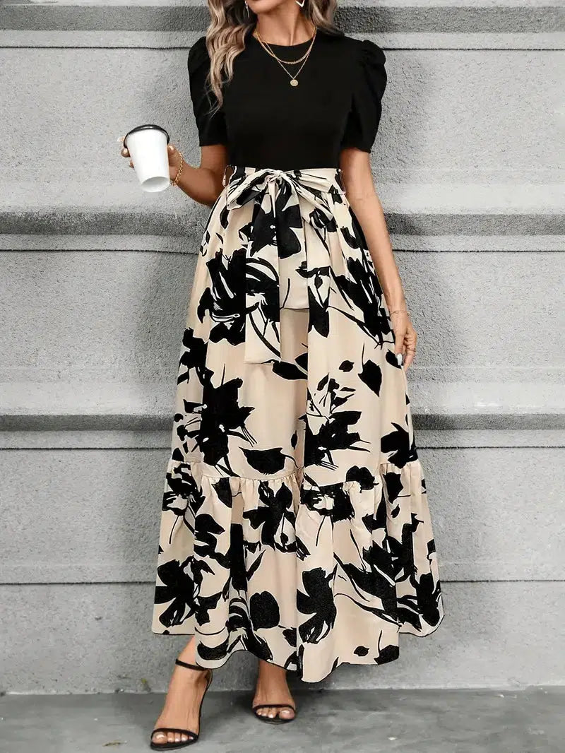 Front view of women's black and beige floral printed maxi dress with puff sleeves, tie waist, and tiered skirt detail.