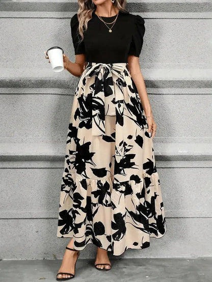 Front view of women's black and beige floral printed maxi dress with puff sleeves, tie waist, and tiered skirt detail.