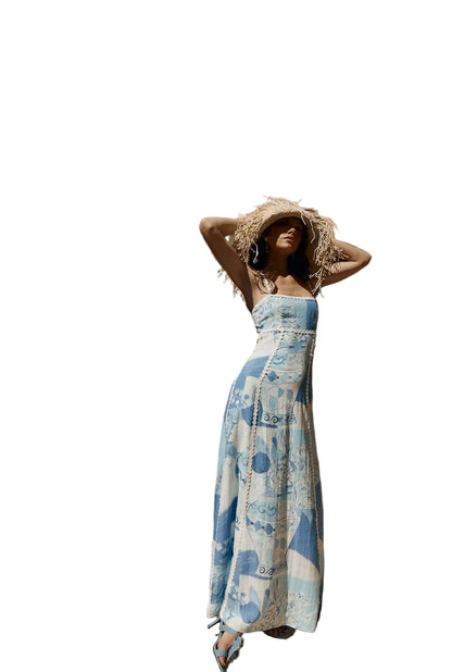 Women's blue and white printed maxi dress with ric rac trim and tie back, styled with a straw hat, perfect for vacation outfits.