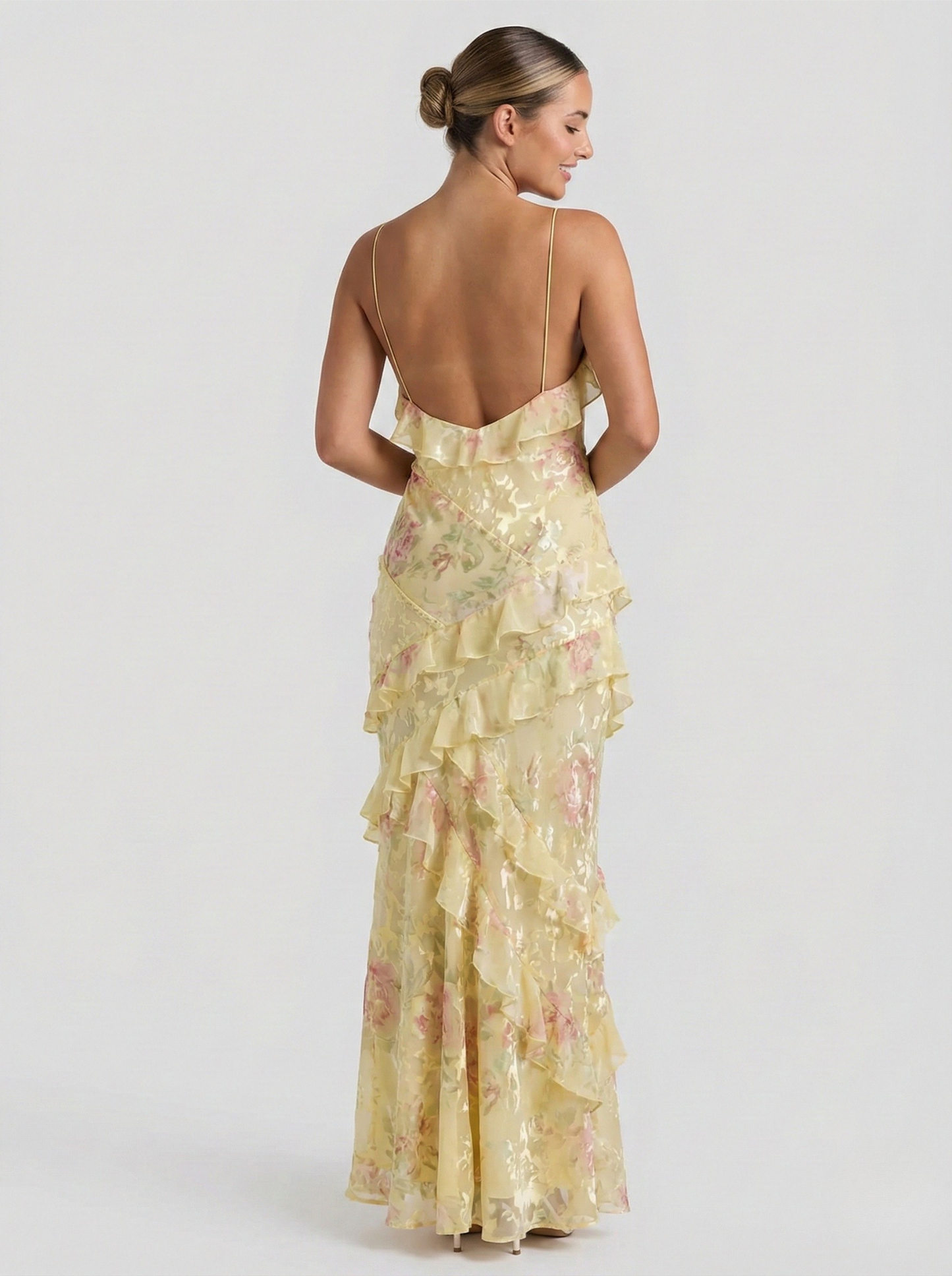 Back view of women's yellow and pink floral maxi dress featuring open back and ruffled detailing.